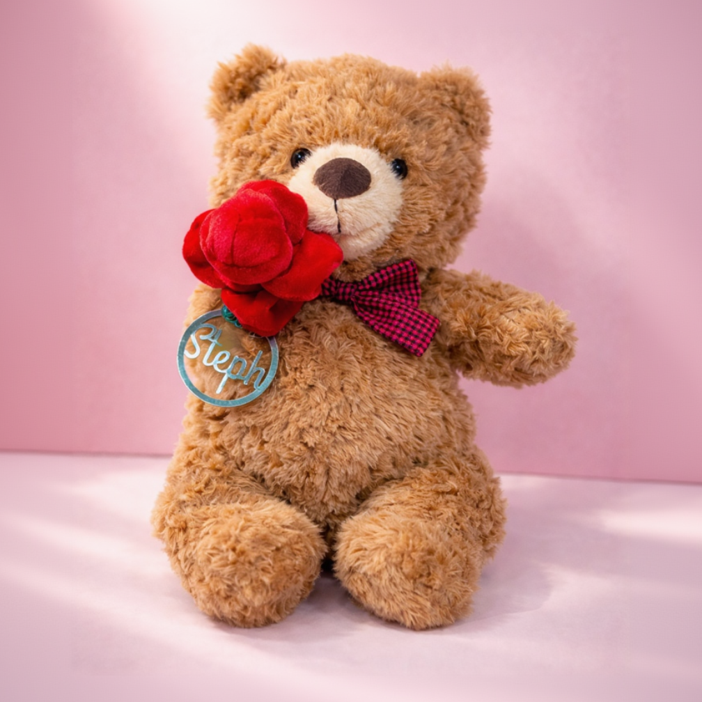 Teddy bear holding a red rose with a pink background