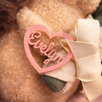 Close-up of a plush with a pink heart-shaped name tag and bow.