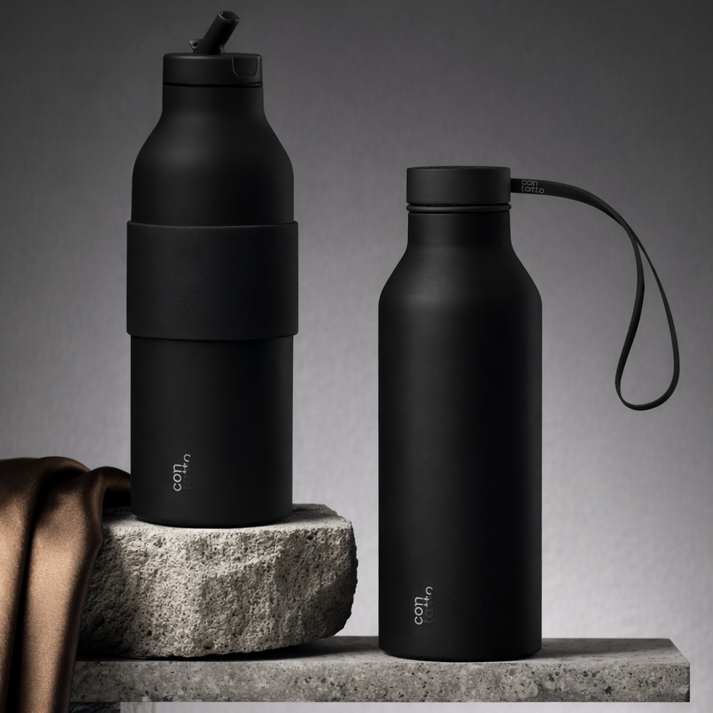 Two black water bottles on a stone surface with a gray background