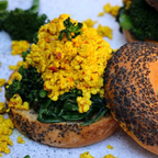 Open-faced sandwich with yellow spread and greens on a white background
