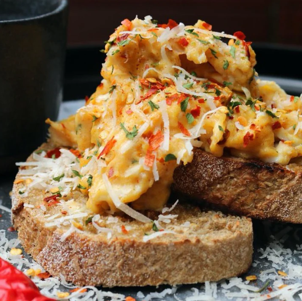 Scrambled eggs with herbs and red pepper flakes on toasted bread