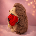 Plush hedgehog holding red roses against a soft pink background
